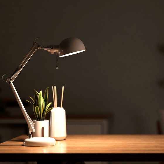 A desk lit by a lamp in the evening