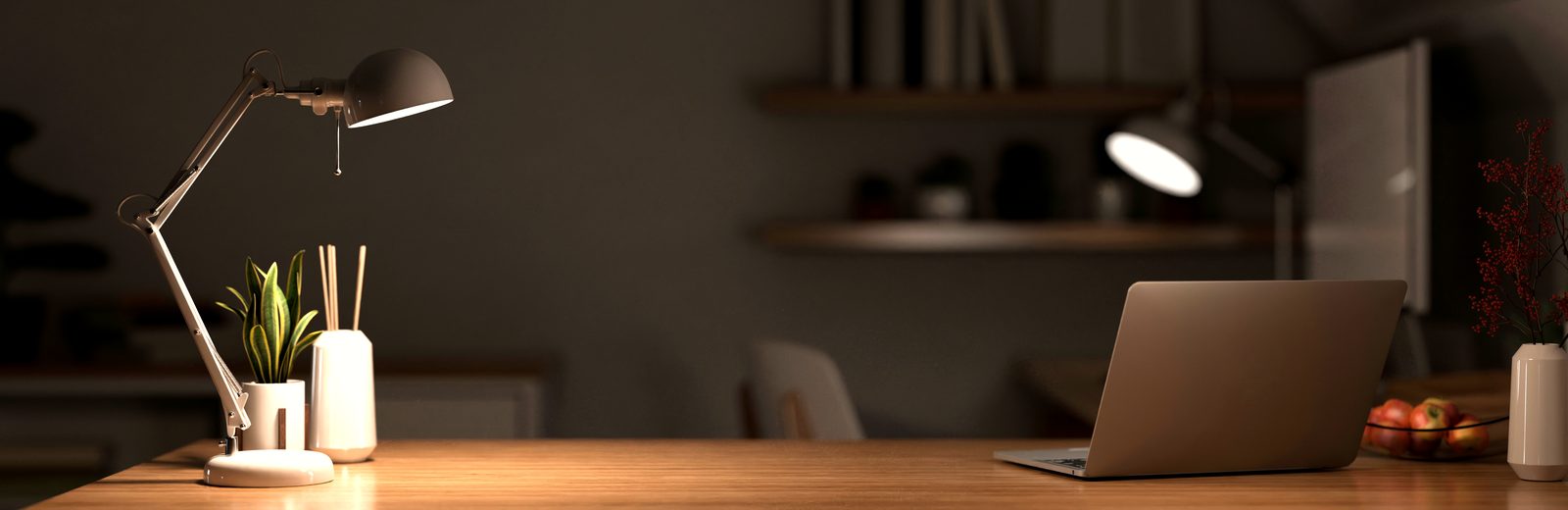 A desk lit by a lamp in the evening